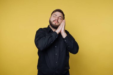 Sakallı bir adam canlı sarı bir duvara karşı duruyor, gözleri kapalı ve elleri çenesinin altında. Huzuru ve hayalleri somutlaştırır, düşüncelerde kaybolur..