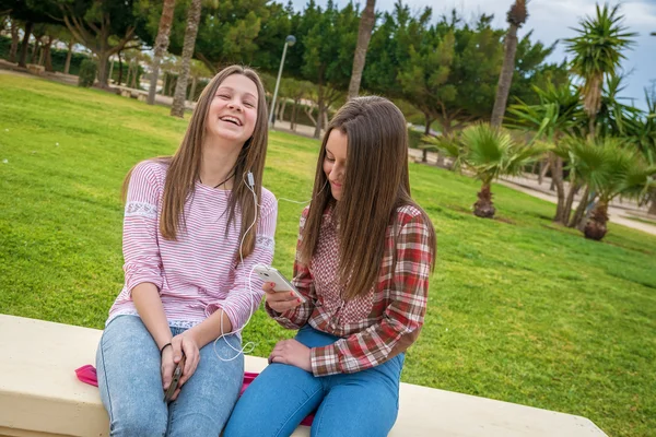 Två tjejer lyssna på musik i hörlurar — Stockfoto