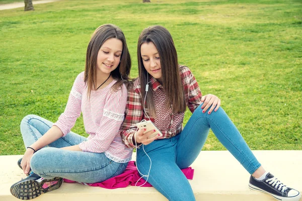 Twee meisjes luisteren naar muziek in oortelefoons — Stockfoto