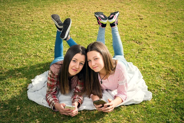 Дві дівчини пишуть в мобільних телефонах — стокове фото