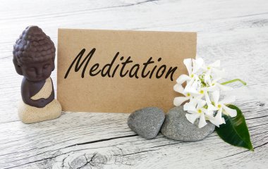 Şirin Buda meditasyonu üzerine meditasyon metni, ahşap masada taşlar ve çiçekler.                               