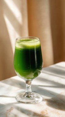 Mermer yüzey üzerinde kristal yeşil sebze suyu, yumuşak altın sabah ışığı, zarif bulanık kaplıca arka plan, temiz kopya alanı ile rafine edilmiş düzen..