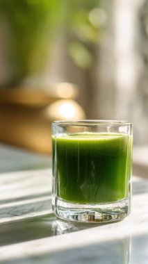 Mermer yüzey üzerinde kristal yeşil sebze suyu, yumuşak altın sabah ışığı, zarif bulanık kaplıca arka plan, temiz kopya alanı ile rafine edilmiş düzen..