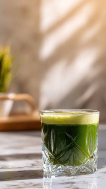 Mermer yüzey üzerinde kristal yeşil sebze suyu, yumuşak altın sabah ışığı, zarif bulanık kaplıca arka plan, temiz kopya alanı ile rafine edilmiş düzen..