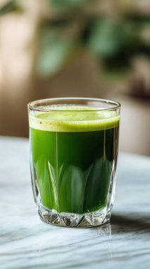 Mermer yüzey üzerinde kristal yeşil sebze suyu, yumuşak altın sabah ışığı, zarif bulanık kaplıca arka plan, temiz kopya alanı ile rafine edilmiş düzen..