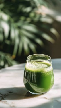 Mermer yüzey üzerinde kristal yeşil sebze suyu, yumuşak altın sabah ışığı, zarif bulanık kaplıca arka plan, temiz kopya alanı ile rafine edilmiş düzen..