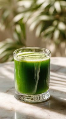 Mermer yüzey üzerinde kristal yeşil sebze suyu, yumuşak altın sabah ışığı, zarif bulanık kaplıca arka plan, temiz kopya alanı ile rafine edilmiş düzen..