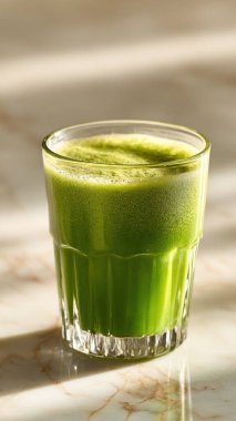 Mermer yüzey üzerinde kristal yeşil sebze suyu, yumuşak altın sabah ışığı, zarif bulanık kaplıca arka plan, temiz kopya alanı ile rafine edilmiş düzen..