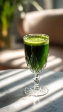 Mermer yüzey üzerinde kristal yeşil sebze suyu, yumuşak altın sabah ışığı, zarif bulanık kaplıca arka plan, temiz kopya alanı ile rafine edilmiş düzen..