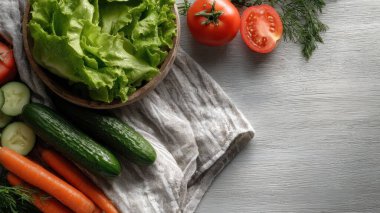 Top view flat lay of fresh salad vegetables lettuce, tomato, cucumber, and carrot on rustic background with copy space, bright natural light, healthy food concept, clean realistic style for website or print use.