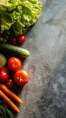 Top view flat lay of fresh salad vegetables lettuce, tomato, cucumber, and carrot on rustic background with copy space, bright natural light, healthy food concept, clean realistic style for website or print use.