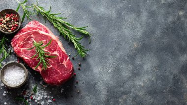 Top view flat lay of raw steak, rosemary, salt, and pepper on rustic background with copy space, soft natural light, realistic texture, cooking preparation concept, clean professional style for website or print.