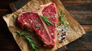 Top view flat lay of raw T-bone steak with rosemary, salt, and pepper on rustic wooden background with copy space, warm natural light, realistic texture, gourmet cooking concept, professional style for website or print use.