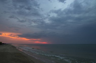 Bulutlu hava ve manzarada denizin üzerinde gün batımı