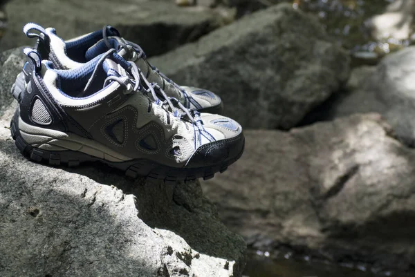 A pair of hiking shoes stand on granite stones