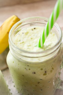 Cam kavanozlarda ıspanaklı, kerevizli ve muzlu sağlıklı yeşil smoothie, dikey görüntü