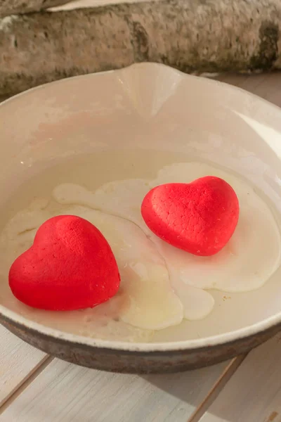 cooked egg with red hearts in a fryer, concept of belarusian revolution
