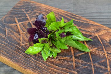 Yeşillikleri karıştır. Kesme tahtasında yeşil ve mor fesleğen. Yemek arkaplanı. Üst görünüm