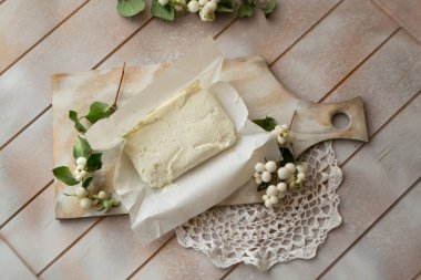 Taze beyaz süzme peynir, eski püskü bir tahta üzerinde ahşap bir masanın üstünde.