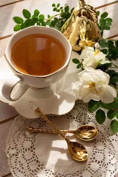 Chá em uma xícara branca de porcelana e pires, com rosa branca — Fotografia de Stock
