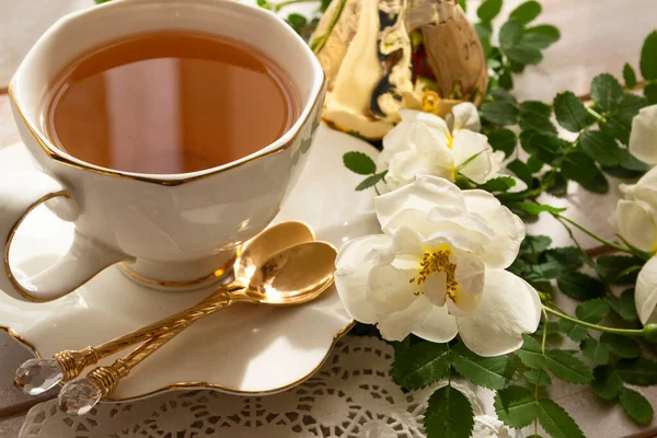 Tasse de thé et branche de petites roses blanches sur table rustique — Photo