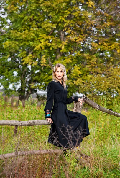 Vacker blond kvinna i svart klänning i sommardag, utomhus — Stockfoto