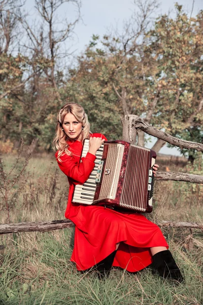 Mulher retrô em traje tradicional com um acordeão, em um campo — Fotografia de Stock