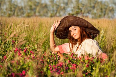Şapkalı bir çiçek alanında, ou romantik genç bir kadın portresi