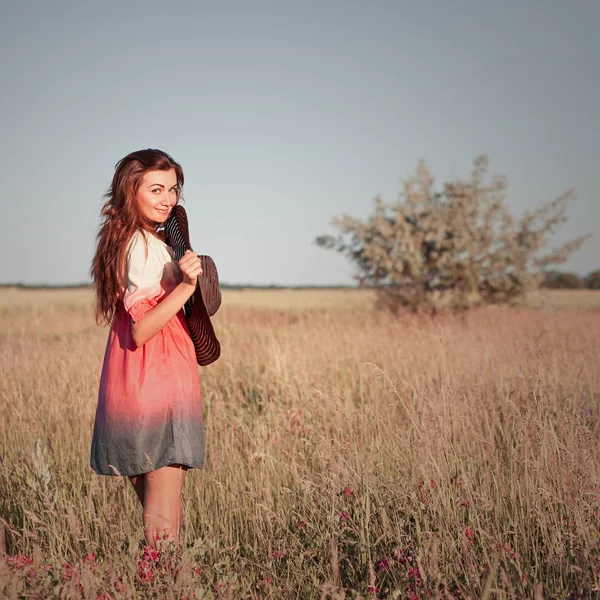 Romantische jonge vrouw met hoed tegoed op weide in warme zomerdag — Stockfoto