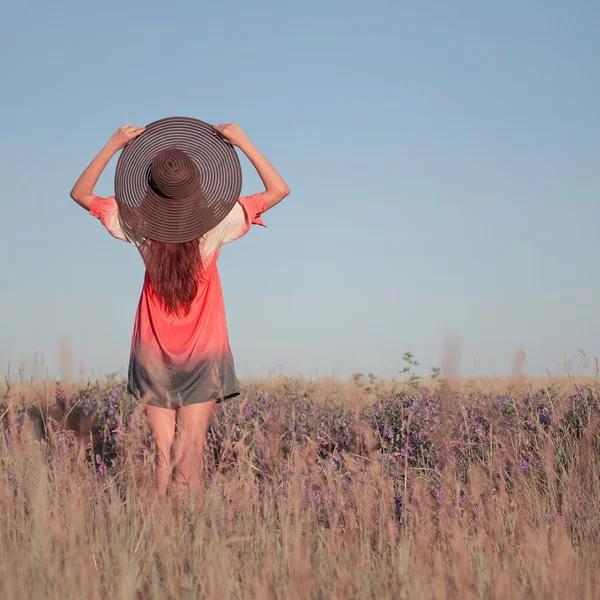 Romantique jeune femme en chapeau debout avec ses bras levés vers elle — Photo