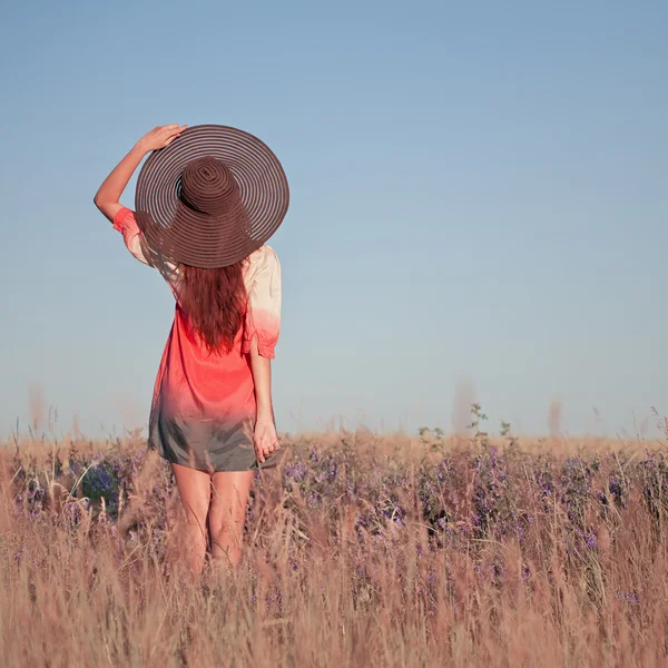Mujer joven romántica con sombrero de pie con los brazos levantados hacia ella — Foto de Stock