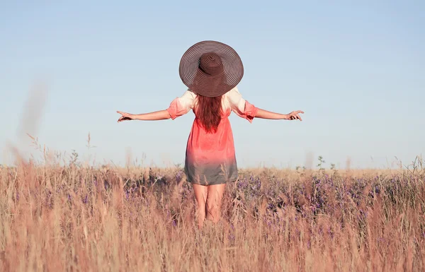 Romantique jeune femme en chapeau debout avec ses bras levés vers elle — Photo