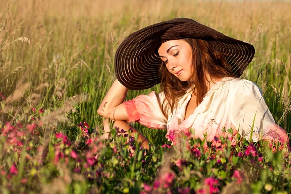 Retrato de una joven romántica con sombrero en un campo de flores, ou — Foto de Stock