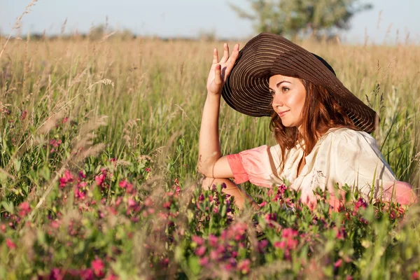 Retrato de uma jovem mulher romântica em chapéu em um campo de flores, ou — Fotografia de Stock