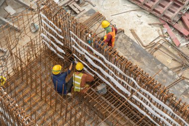 İnşaat işçileri altında vinç ve kazıcılarla çalışan yoğun endüstriyel hava manzarası. Çelik kaplı döşeme öncesi beton döşeme manzarası. Yüksek binalı mimari bina geliştirme.