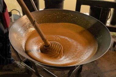 Asyalı bir adam haşlanmış hindistan cevizi şekeri veya kamış üretim süreci, hammadde, Amphawa, Tayland. Geleneksel kültür yaşam tarzı. Yerel tatlı yiyecekler. 