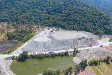 Makine kazıcı kamyonlarının hava görüntüsü dağ tepeleriyle dolu taş ocağında kömür madenciliği ya da maden cevheri kazıyor. Fabrika endüstrisinde doğa manzarası. Çevre kaynakları