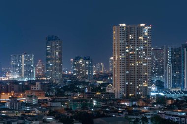 Ofis binalarının pencereleri. Şehir merkezindeki Bangkok City 'de geceleri cam mimari ön cephe tasarımı aydınlatılmış. Odalardaki ışıklar.