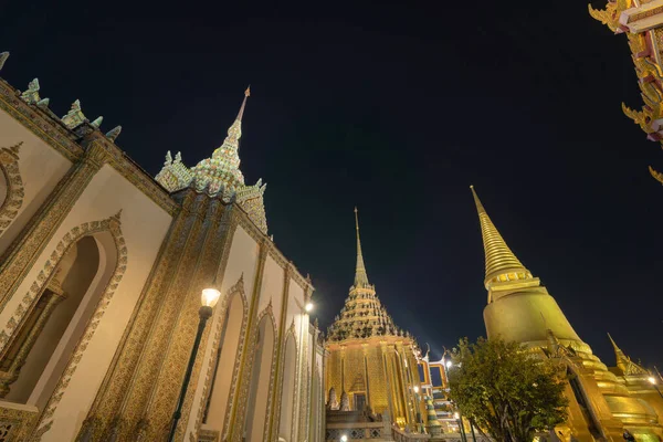 Golden pagoda at Temple of the Emerald Buddha in Bangkok, Thailand. Wat Phra Kaew and Grand palace in old town, urban city. Buddhist temple, Thai architecture. A tourist attraction at night.