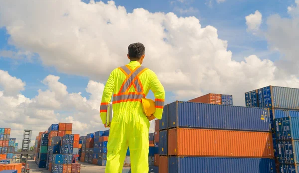 Asian logistic worker engineer man working in cargo container warehouse industry factory site in export, import, and transportation concept. Business people lifestyle. Distribution service.