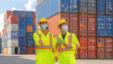 Bir grup hasta lojistik mühendisi kargo konteynerinde çalışıyor. Depo sanayi bölgesinde maske takıyor. İhracat, ithalat konsepti. İş adamları. Corona virüsü ve sağlık hizmetleri.