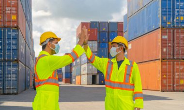 Bir grup hasta lojistik mühendisi kargo konteynerinde çalışıyor. Depo sanayi bölgesinde maske takıyor. İhracat, ithalat konsepti. İş adamları. Corona virüsü ve sağlık hizmetleri.