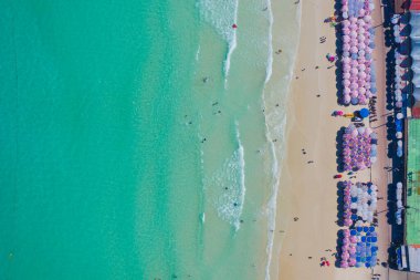 Aerial top view of umbrellas on beach, shore and clear blue turquoise seawater, Andaman sea in summer season. Water in ocean material surface pattern texture wallpaper background.
