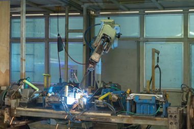 Çelik akıllı robot kaynak sistemi otomatik üretim makinesi motoru fabrikada, endüstriyel metal tedarik zinciri teknoloji üretim teçhizatı işletim deposunda. Kaynak kıvılcımları.
