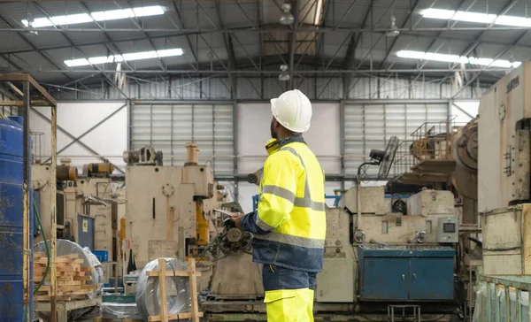 Black African American man, an engineer or worker working in manufacturing factory with equipment machine engine production system work, technology in operation in industry plant in warehouse