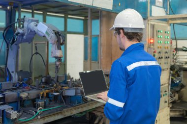 Batılı adam, Kafkasyalı, mühendis ya da işçi akıllı kaynak yapan robot el sistemi otomatikman imalat makinesini kontrol etmek için dizüstü bilgisayar aygıtı kullanır. İnsanlar