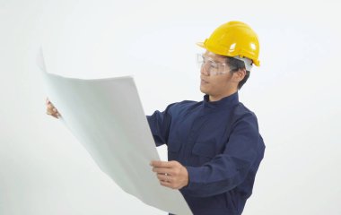 Güvenlik kaskı ve koruyucu gözlüklü Asyalı genç mühendis portresi. Elinde çizim planı var. İnşaat planı beyaz arka planda izole edilmiş.