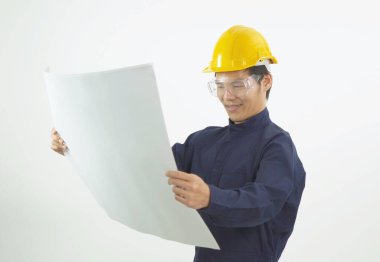 Güvenlik kaskı ve koruyucu gözlüklü Asyalı genç mühendis portresi. Elinde çizim planı var. İnşaat planı beyaz arka planda izole edilmiş.