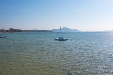Tatil gezisi sırasında yaz mevsiminde Phuket adası yakınlarında mavi turkuaz deniz suyunda bir yelkenli. Andaman Okyanusu, Tayland. Mavi bulutlu turistik bir yer..