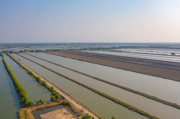 Aerial top view of natural sea salt ponds. Farm field outdoor. Material in traditional industry in Thailand. Asia culture. Agriculture irrigation. River reflection.